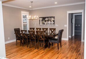 Une salle à manger avec une table et des chaises en bois, un lustre et un tableau au mur.
