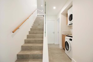A staircase leading to a door, a washing machine, and a wooden handrail. - Elsa - Little Cove (Noosa Heads)