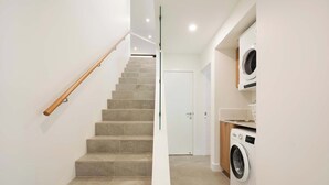 A staircase leading to a door, a washing machine, and a small kitchen area.