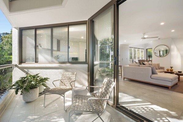 A modern living room with a sofa, a dining table, and a large window.