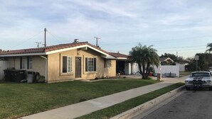 A single-story house with a front yard, a driveway, and a parked car. - Minutes to Disneyland, Knotts, Wild Rivers, Anaheim Conv Ctr, Angels, Ducks, HOB (Orange)