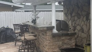 An outdoor patio with a stone bar, seating, and a pergola overhead. - Minutes to Disneyland, Knotts, Wild Rivers, Anaheim Conv Ctr, Angels, Ducks, HOB (Orange)