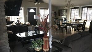 A spacious living room with a large sofa, a dining table, and a coffee table with decorative items. - Minutes to Disneyland, Knotts, Wild Rivers, Anaheim Conv Ctr, Angels, Ducks, HOB (Orange)
