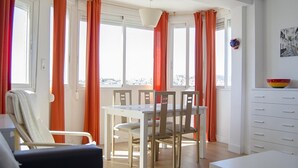 A bright room with a dining table, chairs, and a sofa.