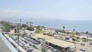 A coastal cityscape with a parking lot, buildings, and a lighthouse in the distance.