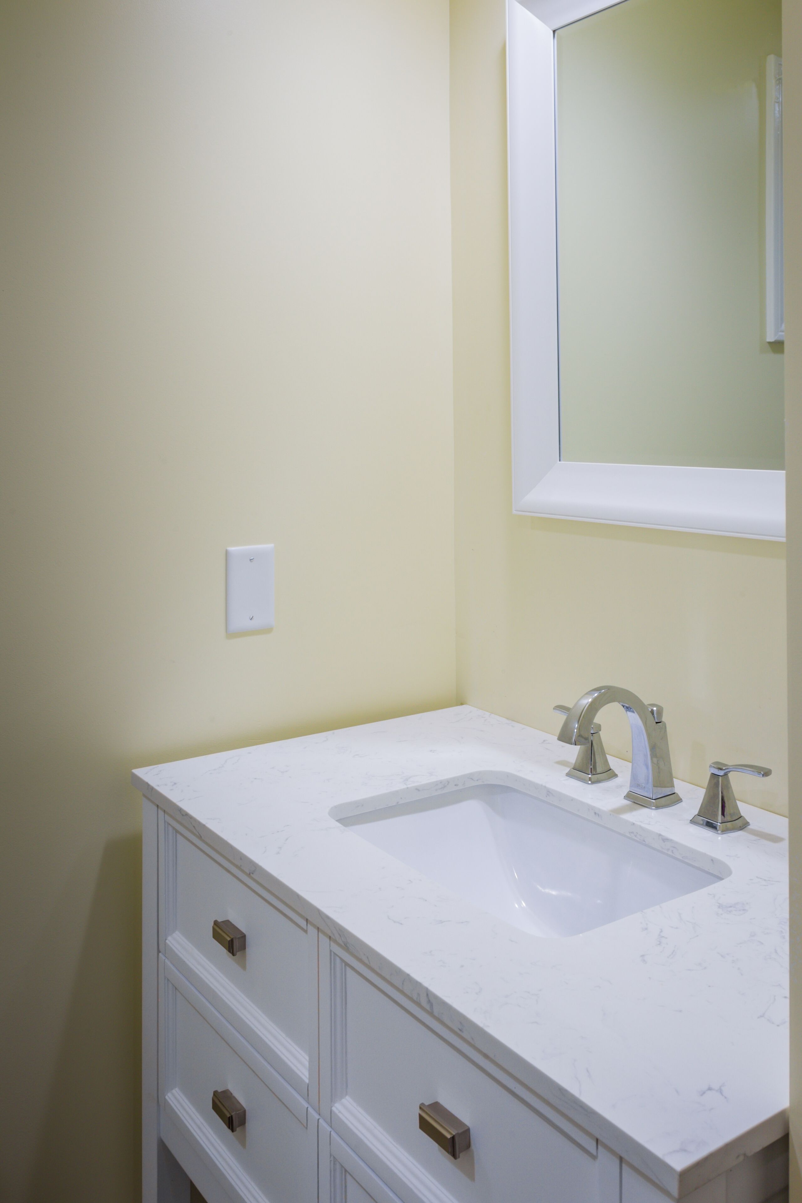 A bathroom with a white sink, a mirror above it, and a light switch on the wall.