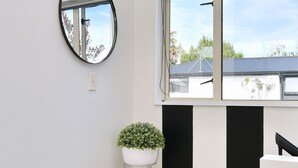 Une pièce avec une grande fenêtre, un miroir rond et une plante en pot.