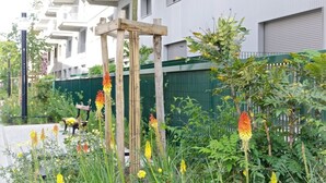 A residential building with balconies, a wooden structure in the garden, and various plants. - Nice apartment for 4 with parking, near Cité du Vin (Bordeaux)