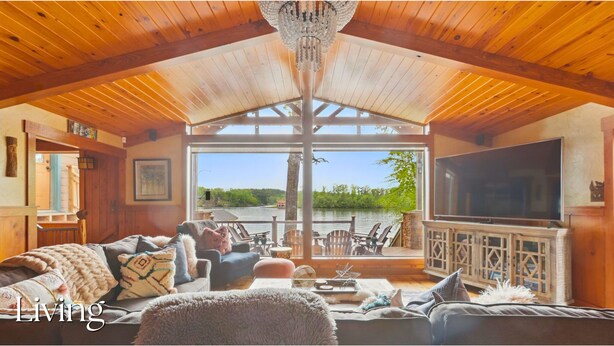 Una sala de estar acogedora con televisor grande, asientos cómodos y vista a un lago.