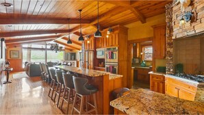 Una cocina amplia con armarios de madera, encimera de granito y chimenea de piedra.