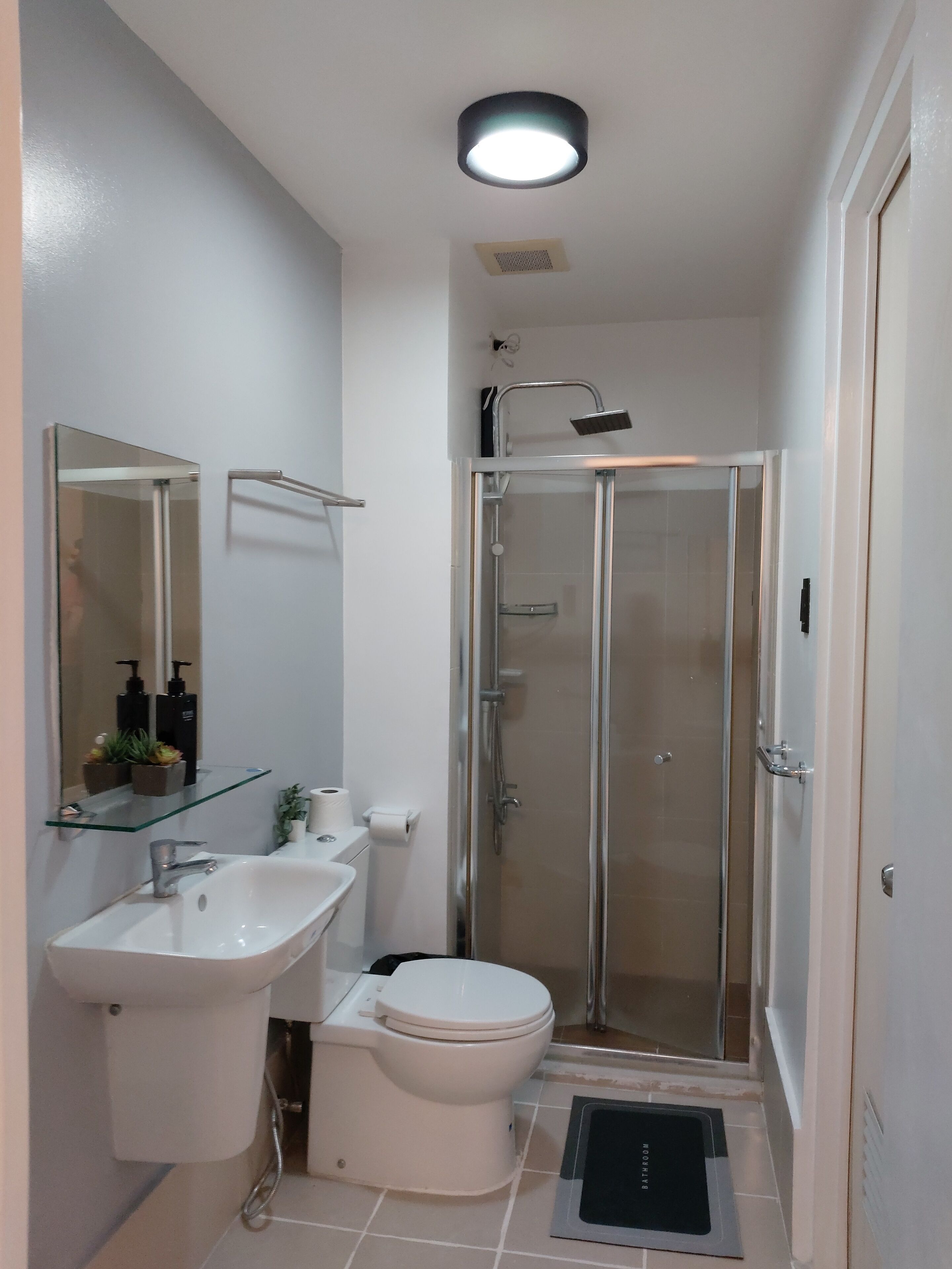 Une salle de bain moderne avec une douche à parois de verre, un lavabo blanc et des toilettes.