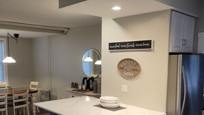Een moderne keuken met een groot kookeiland, roestvrijstalen apparatuur, en een eethoek met witte stoelen.