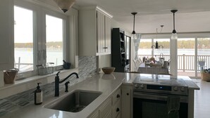 Une cuisine moderne dotée d’une grande fenêtre, d’un four encastré et d’un coin repas offrant une vue sur un lac.