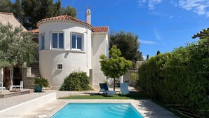 Una casa con piscina, patio con sedie e giardino.