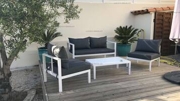 Een terras met witte meubels en potplanten.