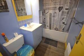 Bathroom features a sink, toilet, and shower area with a curtain.