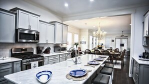A modern kitchen with white cabinets, stainless steel appliances, and a central island with seating. - 1-14 Guest: Pool/Fire Pit/Bikes/Putting Green/Polaris Ranger Included Aug-Dec 25 (St Simons)