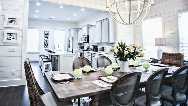 A modern kitchen with white cabinets, a dining area with a wooden table, and a chandelier. - 1-14 Guest: Pool/Fire Pit/Bikes/Putting Green/Polaris Ranger Included Aug-Dec 25 (St Simons)