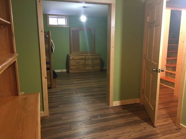 A hallway leading to a bedroom with a wooden dresser and a mirror.