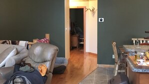A living room with a leather couch, a dining area with a kitchen counter, and a hallway with a wooden ceiling. - Adirondack Experience (Old Forge)
