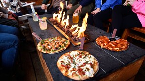 A long table with three pizzas and a drink. - Anchor Inn Resort (Lincoln City)