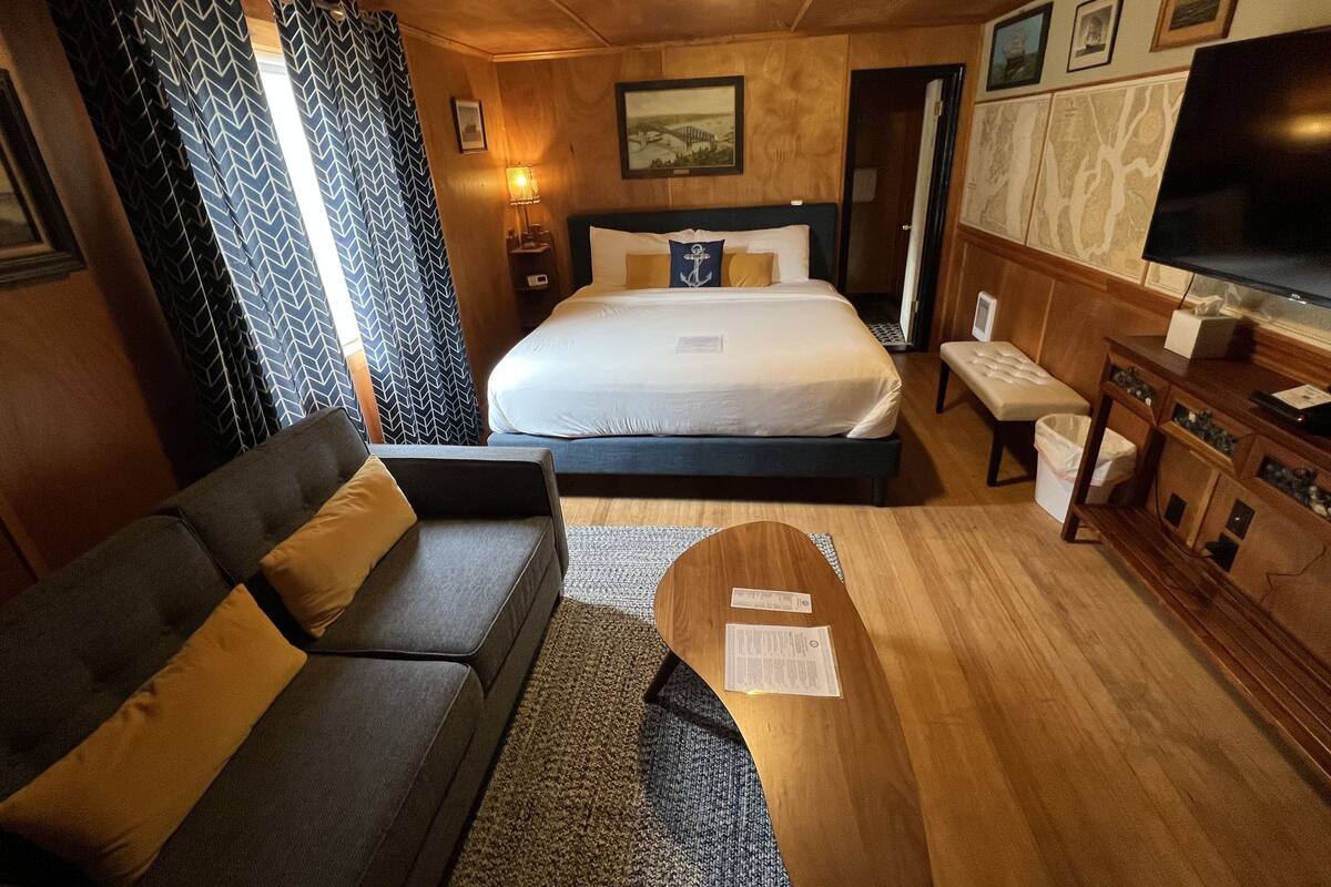 A hotel room with a bed, a sofa, a TV, and a wooden cabinet.