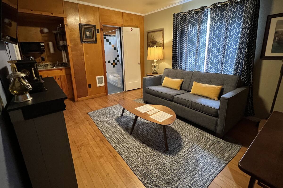 A compact living space with a sofa, coffee table, and a kitchenette area.