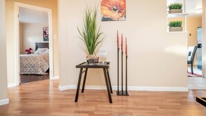 Un hall d’hôtel avec un plancher en bois, une plante en pot, un tableau et un ensemble de bougies.