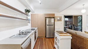 A modern kitchen with white cabinetry, stainless steel appliances, and a wooden floor. - 1-17 Heath Street - Stylish Unit on Heath Street (EVANS HEAD)
