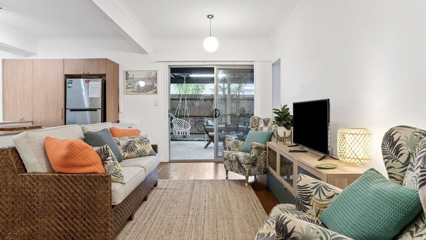 A modern living room with a sofa, armchairs, a TV, and a dining area visible through a glass door. - 1-17 Heath Street - Stylish Unit on Heath Street (EVANS HEAD)