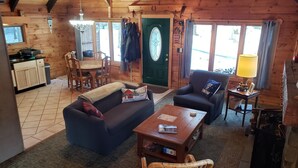 A cozy log cabin interior with a living room, dining area, and kitchen. - 10 min from Stratton! Log Cabin w/ Beautiful Views (South Londonderry)