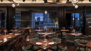 A restaurant with multiple dining tables, chairs, and pendant lighting.
