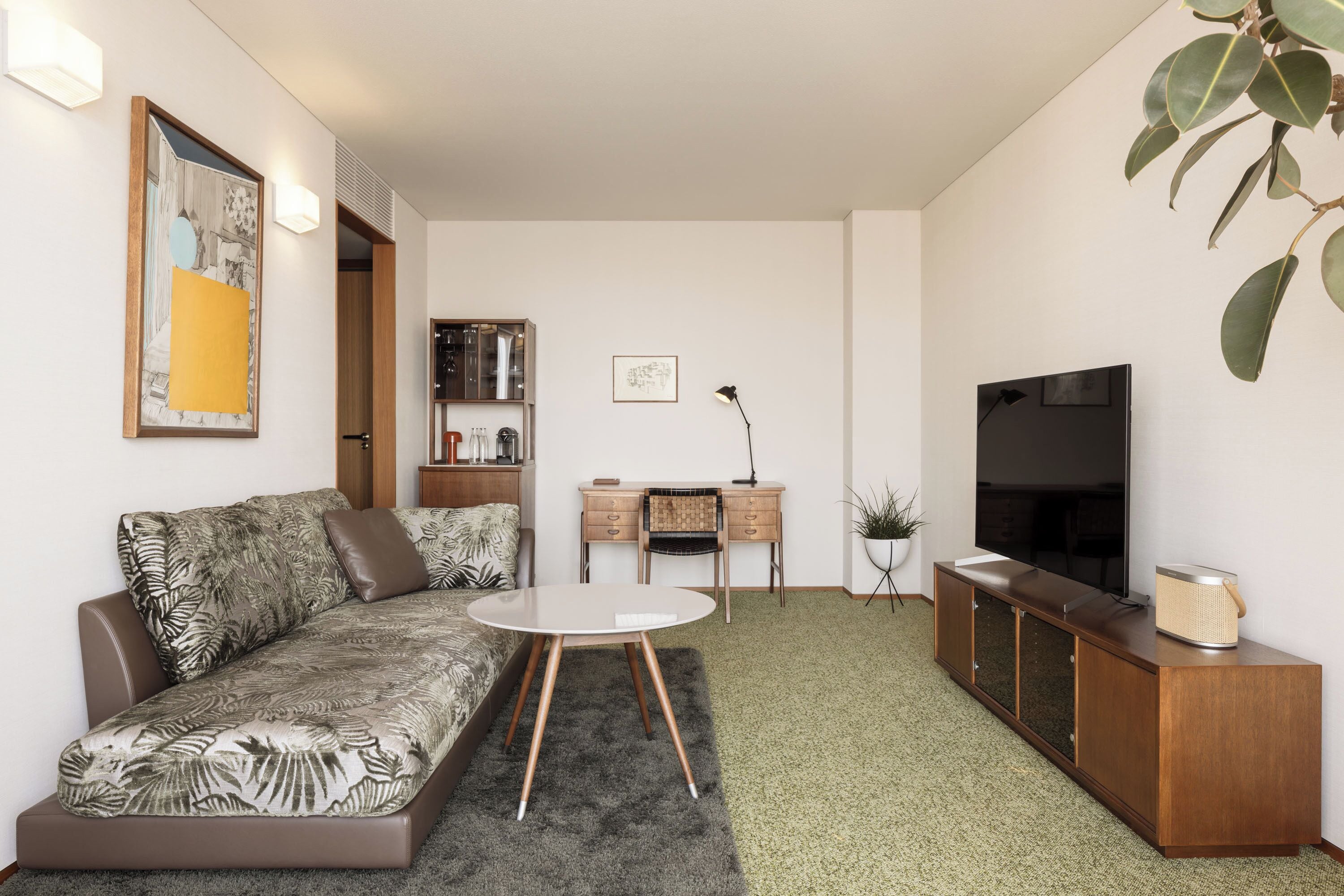 A modern living room with a sofa, a small round table, a TV, and a cabinet.