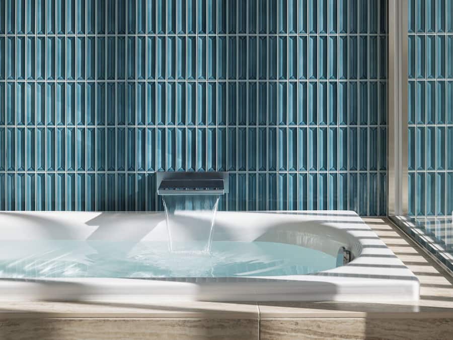 A hot tub with water flowing, set against a wall with a blue pattern.