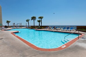 Relax by the pool surrounded by palm trees and lounge chairs.