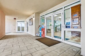 Welcome to our hotel lobby, featuring a spacious area with a herringbone-patterned floor and a reception desk with a glass partition.