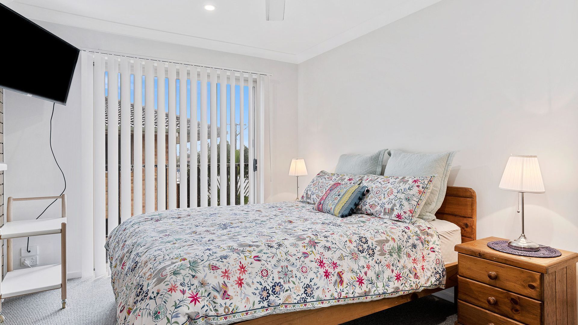 Un dormitorio con cama, mesitas de noche, una silla y televisor.
