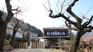 A traditional Japanese house with a wooden exterior and a tiled roof, surrounded by trees and a gravel driveway. - Taisho modern Villa ZEN (Hakone)