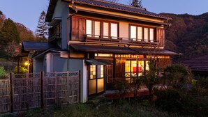A traditional wooden house with a balcony, surrounded by a wooden fence and trees. - Taisho modern Villa ZEN (Hakone)