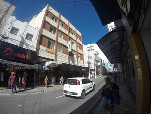 A street view with a hotel sign, shops, and pedestrians. - Hotel São Nicolau (Taubate)