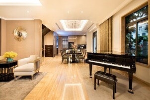 Amplia sala de estar con un piano de cola, comedor y vistas de la ciudad a través de grandes ventanales.