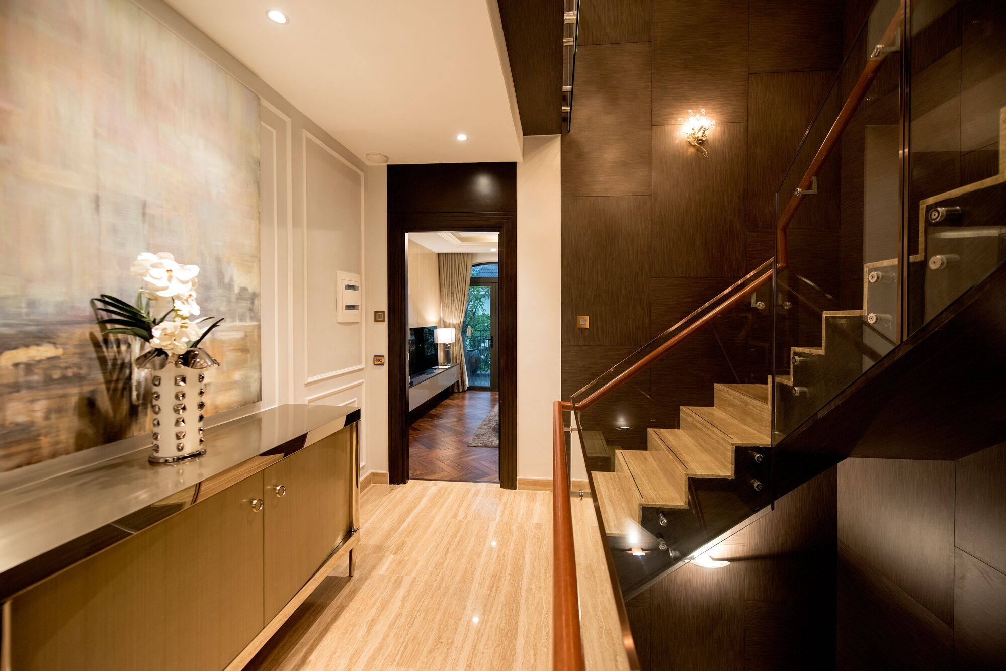 Een modern interieur met een houten trap, een marmeren vloer en een gang die uitkomt op een kamer met uitzicht op groen.
