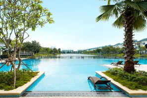 A swimming pool with lounge chairs, surrounded by greenery and a view of buildings in the background. - Icity Lakeview Saigon Villa (Ho Chi Minh City)