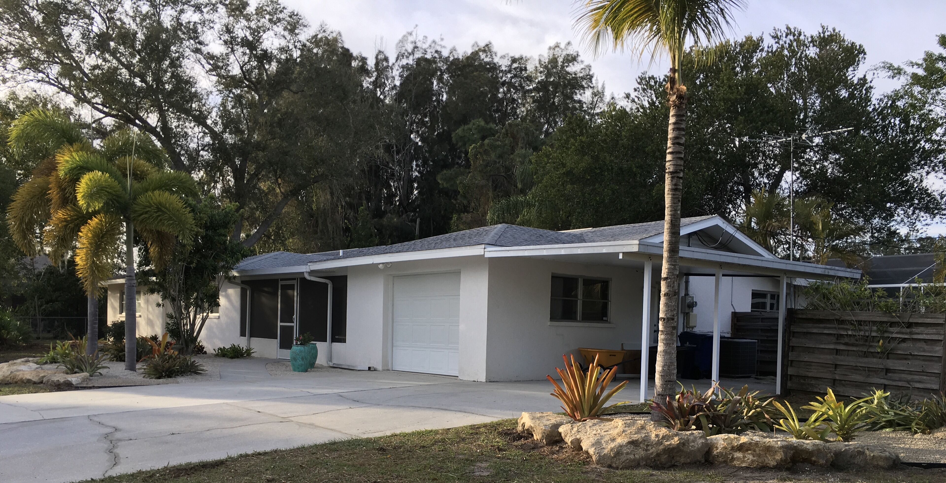 A single-story house with a garage, surrounded by a well-maintained lawn and various plants.