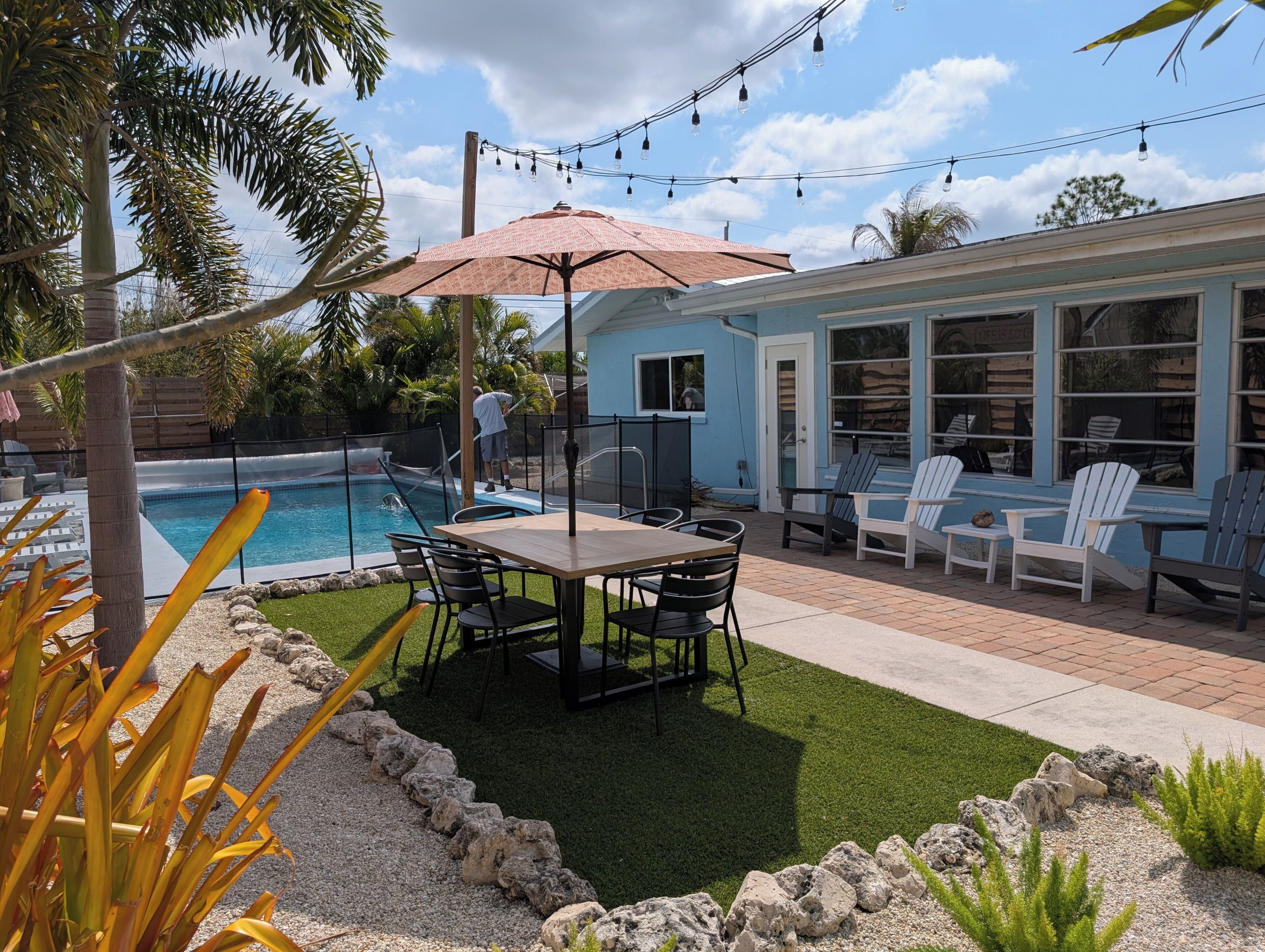 A backyard with a pool, patio furniture, and a covered seating area.