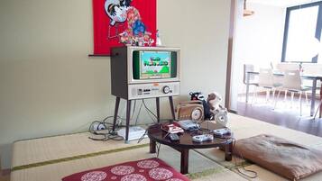 A living room with a retro television, a sofa, and a tatami mat.