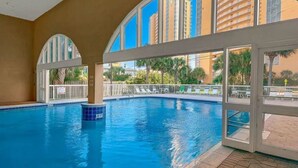 An indoor swimming pool with clear views of tall buildings and palm trees outside. - Labor Day special at Celadon 1201: 3 bed/3 bath beachfront (Panama City Beach)