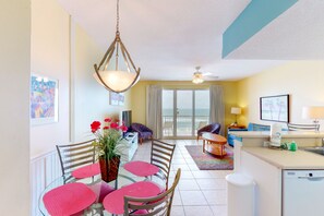 Enjoy meals with family and friends in this spacious living area, featuring a dining table for four and a sliding door leading to a balcony with outdoor views.