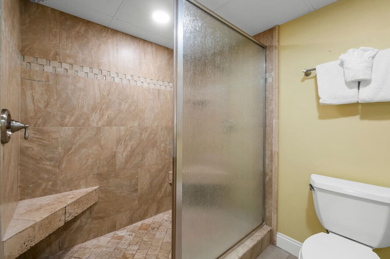 A bathroom with a shower, a toilet, and a towel rack.