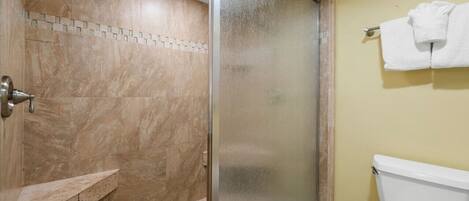A bathroom with a shower, a toilet, and a towel rack.